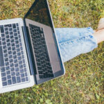 laptop across outstretched legs on the grass
